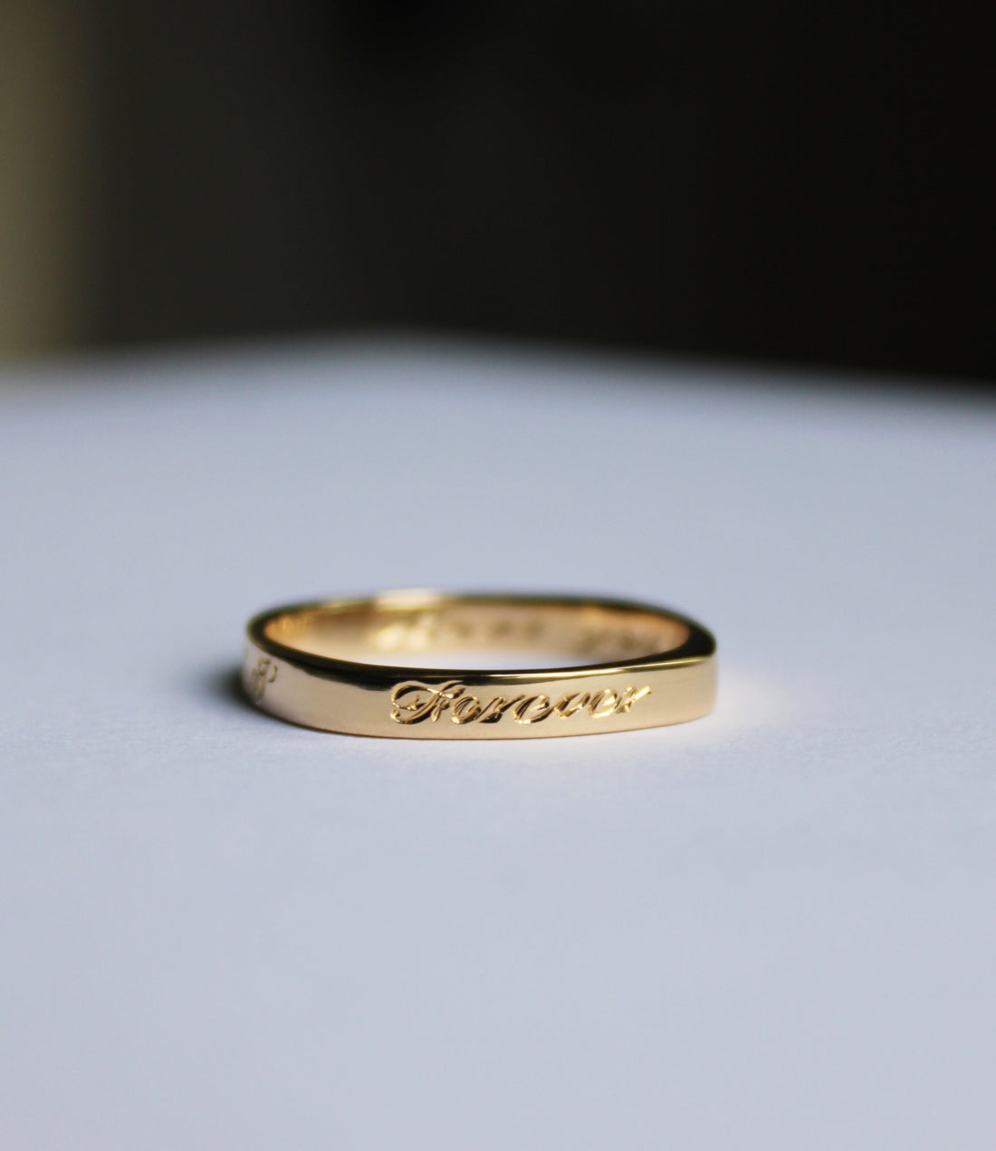 Gold ring with engraved text on a light surface